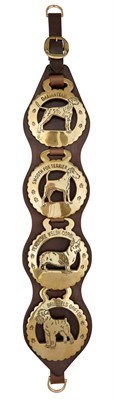Lot 65A - Four Dog Brasses on a Leather Strap Depicting...