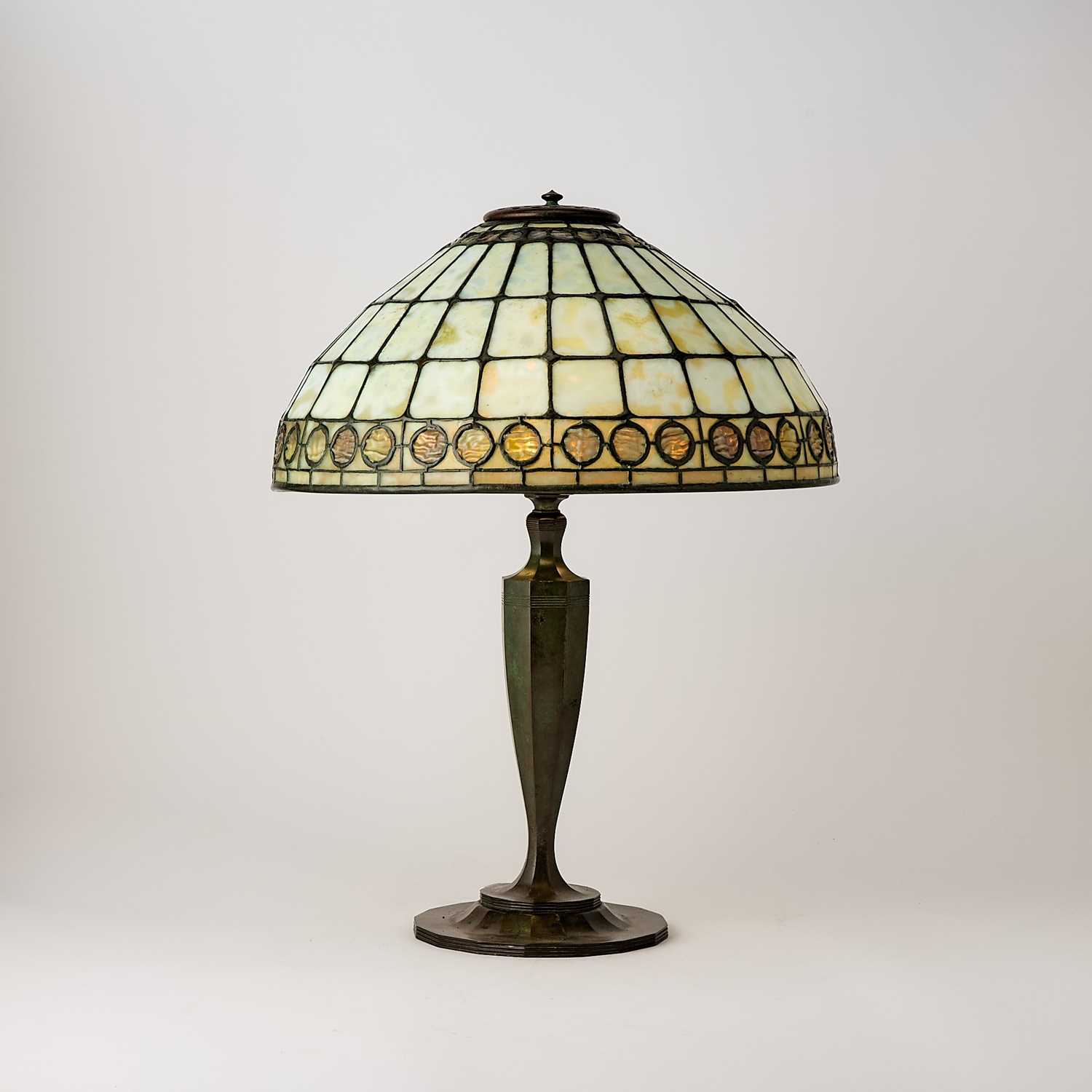 Lot 678 - Tiffany Studios Bronze and Leaded Glass ‘Colonial Faux-Jeweled Band’ Table Lamp