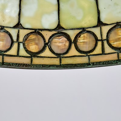 Lot 678 - Tiffany Studios Bronze and Leaded Glass ‘Colonial Faux-Jeweled Band’ Table Lamp