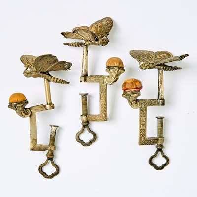 Lot 1234 - Three Silvered Metal and Brass Butterfly Sewing Clamps with Pin Cushions
