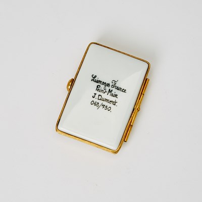 Lot 31 - A porcelain box in the shape of an Annie playbill